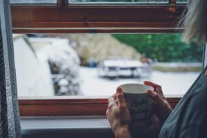 Ein geöffnetes Fenster in einem gemütlichen Raum während des Winters, das frische Luft hereinlässt, um das Raumklima zu verbessern.